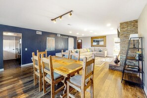Ein modernes Wohnzimmer mit Esstisch, Sofas und einer Küche im Hintergrund.
