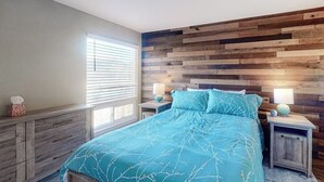 A bedroom with a wooden headboard, a bed with a blue bedspread, bedside tables with lamps, and a window with blinds. - Mountain View Condo with Private Balcony, Gas Fireplace & Free WiFi (Silverthorne)
