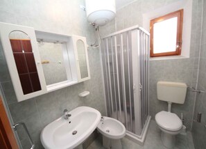 Ein Badezimmer mit Duschkabine, Waschbecken, Bidet und Toilette.