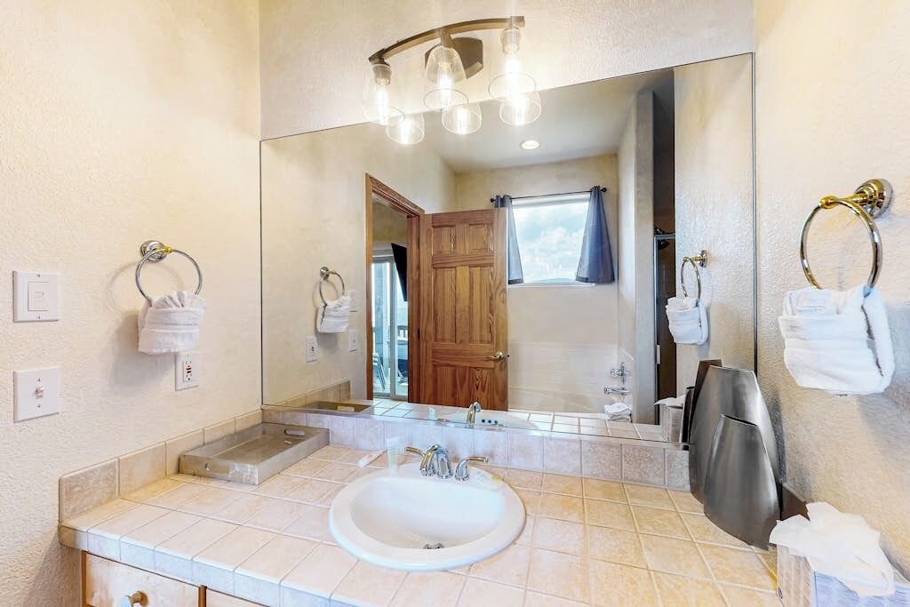 Un baño con un espejo grande, un lavabo, un perchero para toallas y una zona de ducha.