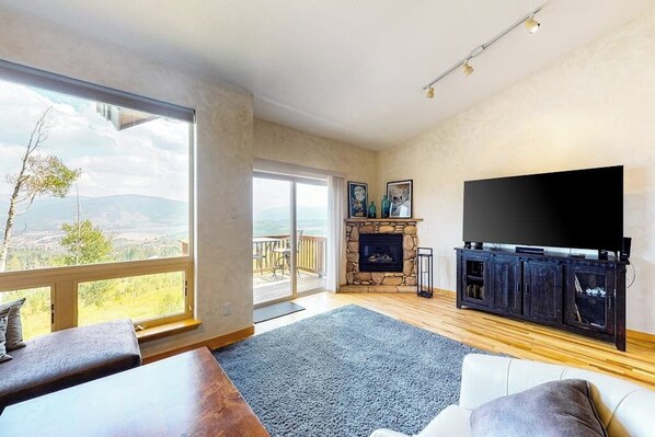 A spacious living room with a fireplace, a large TV, and a balcony with a view. - Mountain view home with high-speed WiFi and washer/dryer (Silverthorne)