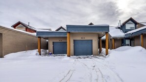 Un bâtiment doté de deux portes de garage, un sol recouvert de neige et un ciel nuageux.