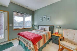 Ein Schlafzimmer mit einem Bett, Nachttischen, einem Sessel und einem Fenster mit Blick.