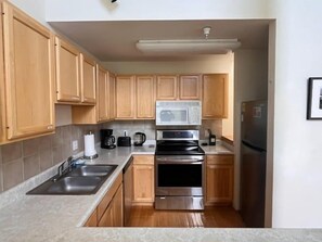 Una cocina compacta con armarios de madera, microondas, estufa y refrigerador.