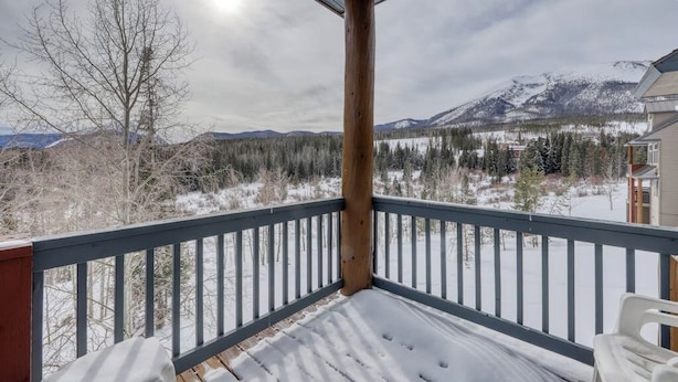 Une terrasse enneigée offrant une vue sur les montagnes et les arbres.