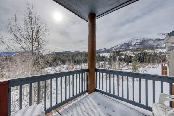 Ein mit Schnee bedeckter Balkon mit Blick auf Berge und Bäume.