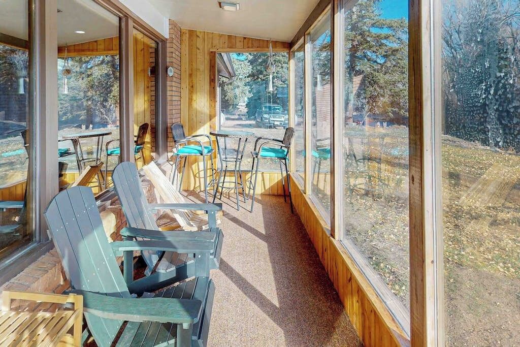 A room with wooden walls, large windows, and a seating area with chairs and tables.