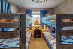 A room with bunk beds, a lamp, and a view through a window. - Spacious cabin with river views, private hot tub, sun room, and full kitchen! (South Fork)