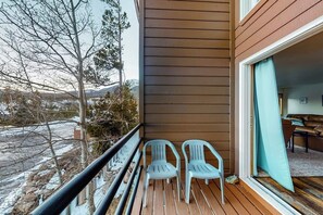Ein Balkon mit zwei Stühlen, einer Holzterrasse und Blick auf eine verschneite Landschaft.