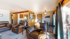 Uma sala de estar com sofá, poltrona e um espaço de jantar com mesa e cadeiras.