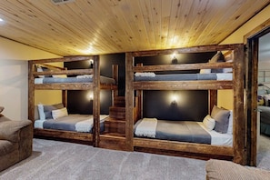 Ein Zimmer mit zwei Etagenbetten, einer Treppe und einem Sofa.