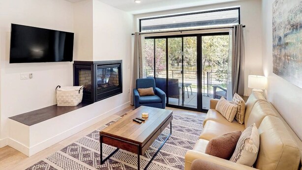 Una sala de estar con sofá, mesa de centro, televisor y chimenea.