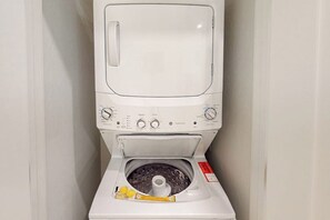 Eine weiße Waschmaschine mit Bedienfeld, Reiniger-Spender und einem roten Sicherheitsschild.