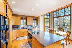 Eine Küche mit Holdekor, einem Kühlschrank, einer Spüle und einem Essbereich mit Stühlen und einem Tisch.