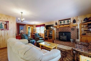 Ein gemütliches Wohnzimmer mit Kamin, Holzwänden und einem Fernseher.