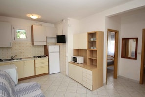 A compact kitchen with white cabinets, a microwave, and a stove. There is a small window and a mirror on the wall. - Holiday apartment with air conditioning and balcony (Rosolina Mare)