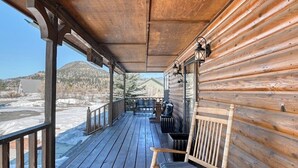 Eine Holzhütte mit Veranda, einer Bank und Blick auf eine verschneite Landschaft.