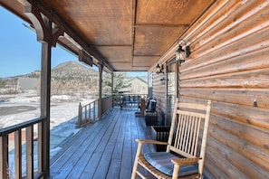 Eine Holzhütte mit Veranda, einer Bank und Blick auf eine verschneite Landschaft.