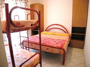 A bunk bed room with a lower bunk, a bed with a floral bedspread, and a wardrobe. - Holiday apartment with air conditioning and terrace (Rosolina Mare)