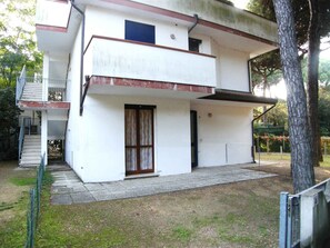 A two-story building with a balcony, a staircase, and a small garden area. - Holiday apartment with air conditioning and terrace (Rosolina Mare)