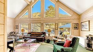Un vaste espace de vie de style loft, doté de hauts plafonds, de grandes fenêtres et d’un coin salon confortable avec un canapé et des fauteuils.