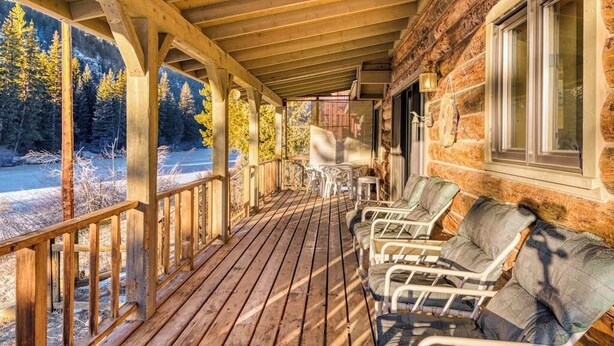 Une terrasse en bois, avec des chaises et une table, donnant sur une zone boisée.