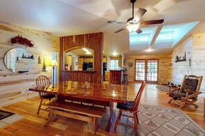 Ein Holzinterieur mit einem Esstisch, Stühlen, einem Deckenventilator und einem großen Spiegel.