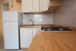 Eine Küche mit einem weißen Kühlschrank, einer Spüle und einem Gasherd.