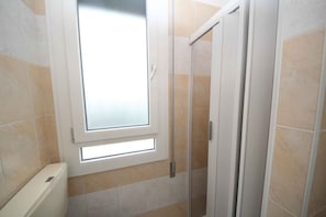 Ein Badezimmer mit Fenster, Dusche und Toilette.