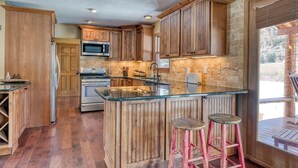 A kitchen with wooden cabinets, a central island with stools, a microwave, and an oven. - Waterfront home on the Rio Grande with washer/dryer, deck, & amazing views (South Fork)