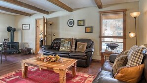 A cozy living room with a fireplace, a sofa, a coffee table, and a window with blinds. - Waterfront home on the Rio Grande with washer/dryer, deck, & amazing views (South Fork)