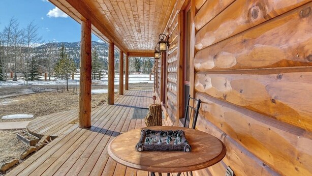 A wooden cabin with a covered porch, a table with a chessboard, and a view of a snowy landscape. - Waterfront home on the Rio Grande with washer/dryer, deck, & amazing views (South Fork)