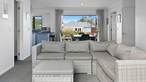 Un salon moderne avec un canapé d’angle, une petite table et une vue sur l’extérieur.