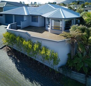 A modern house with a sloped roof, a covered patio, and a garden with young trees. - Relax & Unwind Close to Lake & Town (Taupō)