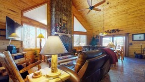 Ein Blockhaus-Interieur mit Kamin aus Stein, Ledersofa und Holzmöbeln.