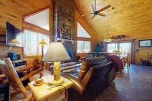 Ein Blockhaus-Interieur mit Kamin aus Stein, Ledersofa und Holzmöbeln.