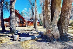 Eine Holzhütte mit einer Holzterrasse, umgeben von hohen Bäumen.