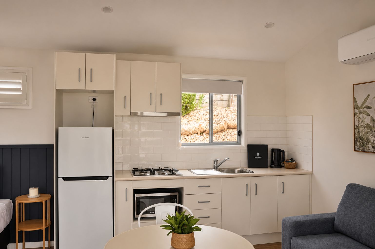 Una cocina compacta con armarios blancos, horno empotrado, cocina a gas y ventana con vistas al exterior.