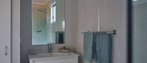A modern bathroom with a large mirror, a sink, and a towel rack with two towels.