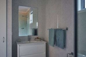 Un baño moderno con un espejo grande, un lavabo y un perchero con dos toallas.