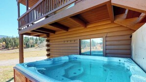 Een hottub voor een houten chalet met een balkon.