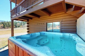 Ein Whirlpool vor einer Holzhütte mit einem Balkon.