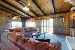 Ein Holzinterieur mit einer Couch, einem Couchtisch und einem Deckenventilator.