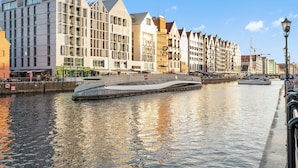 A river with modern buildings and a bridge. - Długa Grobla 10 by Grand Apartments (Gdańsk)
