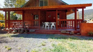 Eine Holzhütte mit Veranda, zwei Tischen und Stühlen.