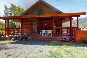 A wooden cabin with a porch, two tables, and chairs. - Charming rural cabin w/ mountain views, sauna, and deck - close to Rio Grande (South Fork)