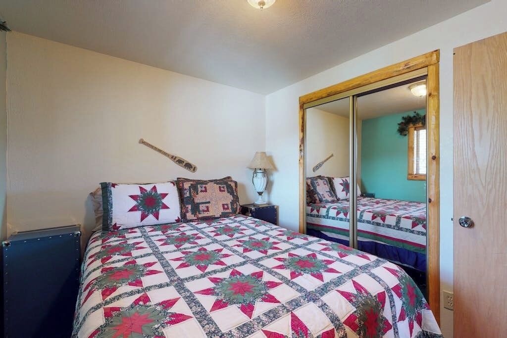 Une chambre à coucher avec un lit, un miroir, une lampe et une porte.