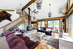 Ein großzügiger Wohnbereich mit Kamin, Ledersofas, einem Couchtisch und einer Treppe.