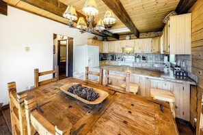 Ein Holzespeisesaal mit Stühlen, eine Küche mit Holzschränken und eine Chandelier.