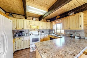 Eine Küche mit Holzschränken, Granit-Arbeitsplatten, einem weißen Kühlschrank und einem Fenster, das für natürliches Licht sorgt.